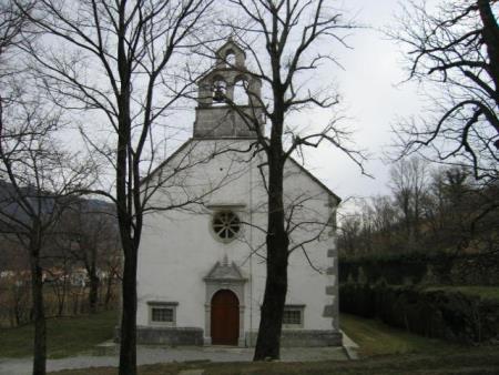 Na fotografiji je Podružnična cerkev sv. Kozme in Damjana v Podbrju obdana z drevesi